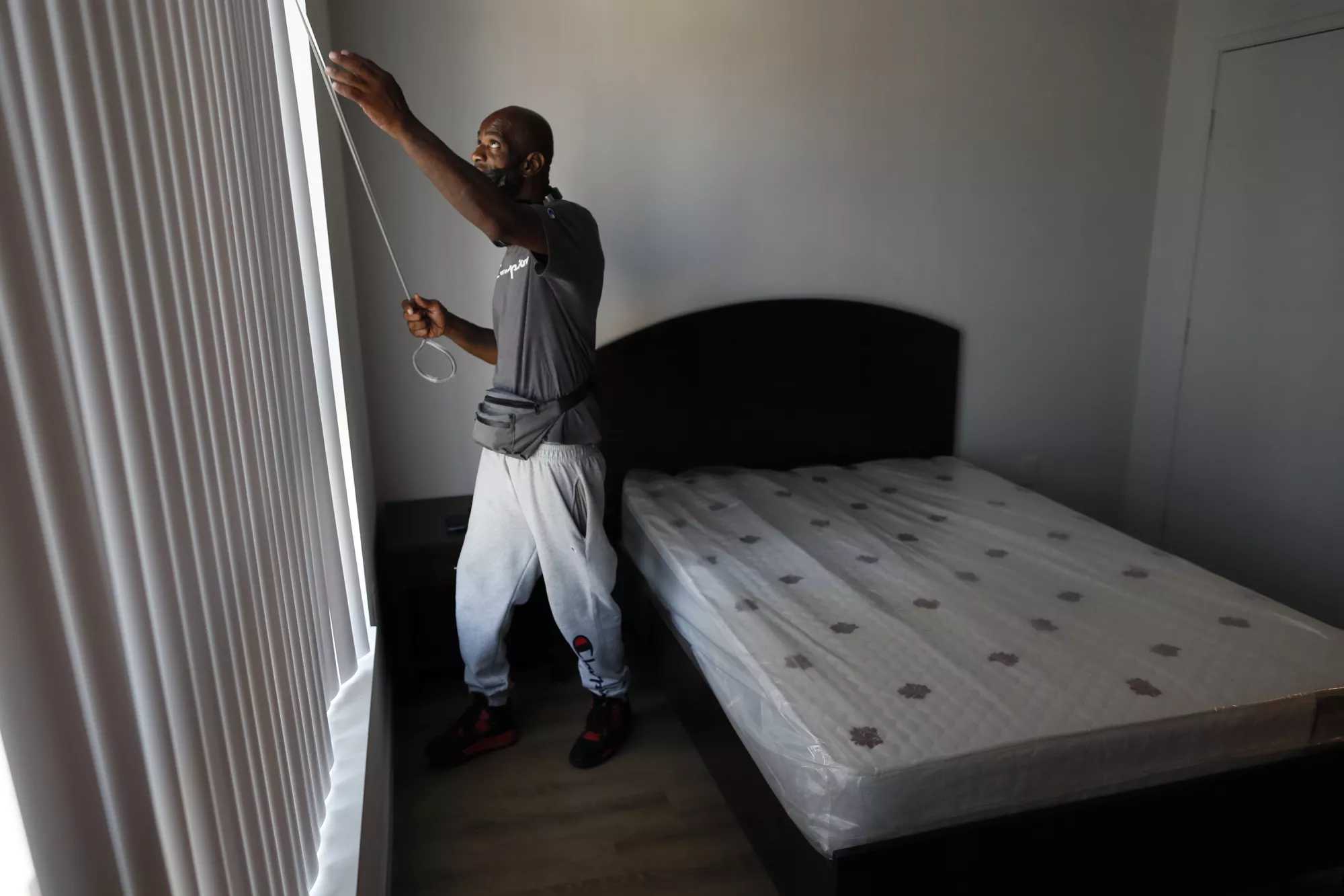 Donald Winston adjusts the blinds moments after moving into his new apartment — the first-ever home of his own. ©Robert Gauthier/Los Angeles Times