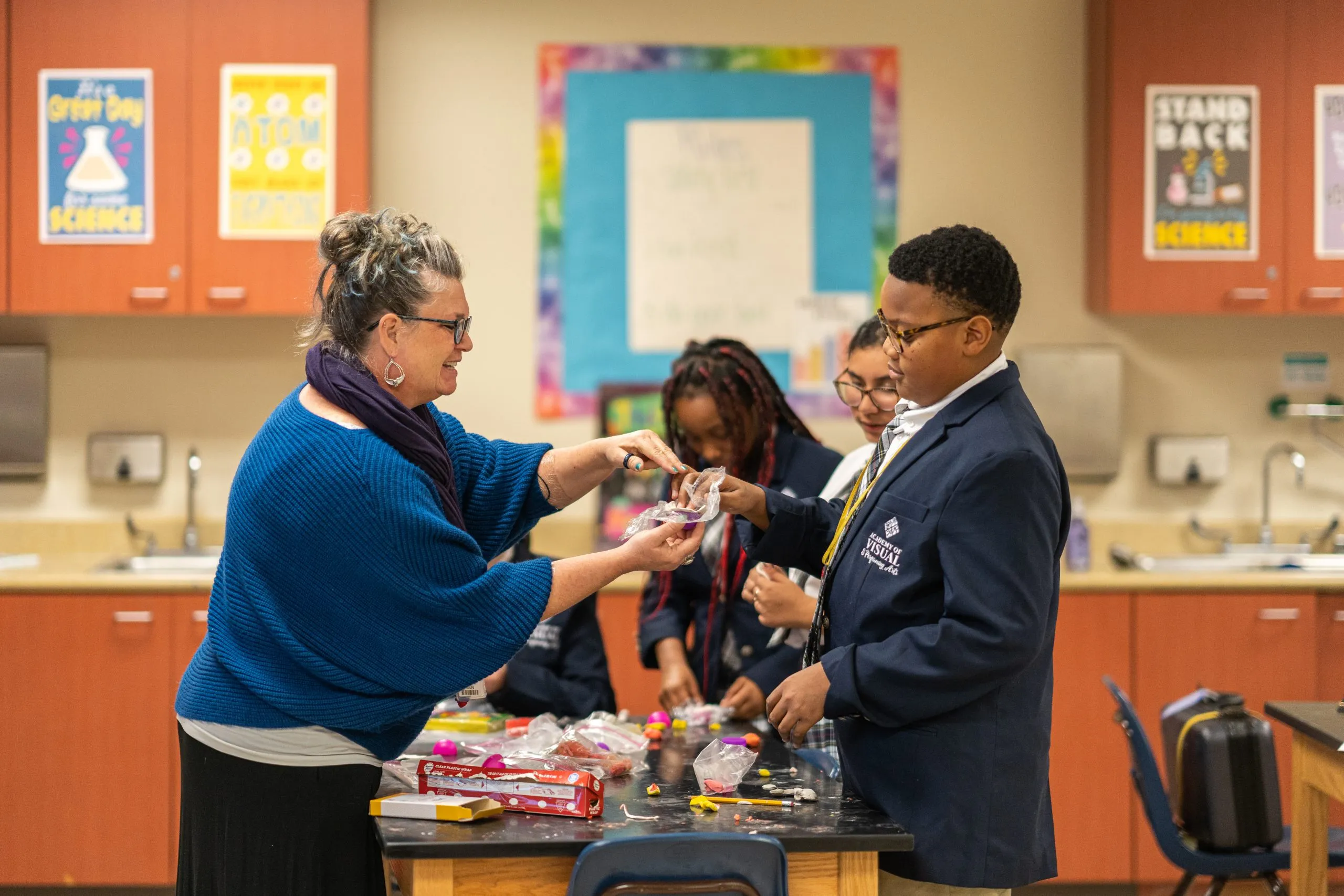 Science teacher works with Academy students in the classroom on a science project.