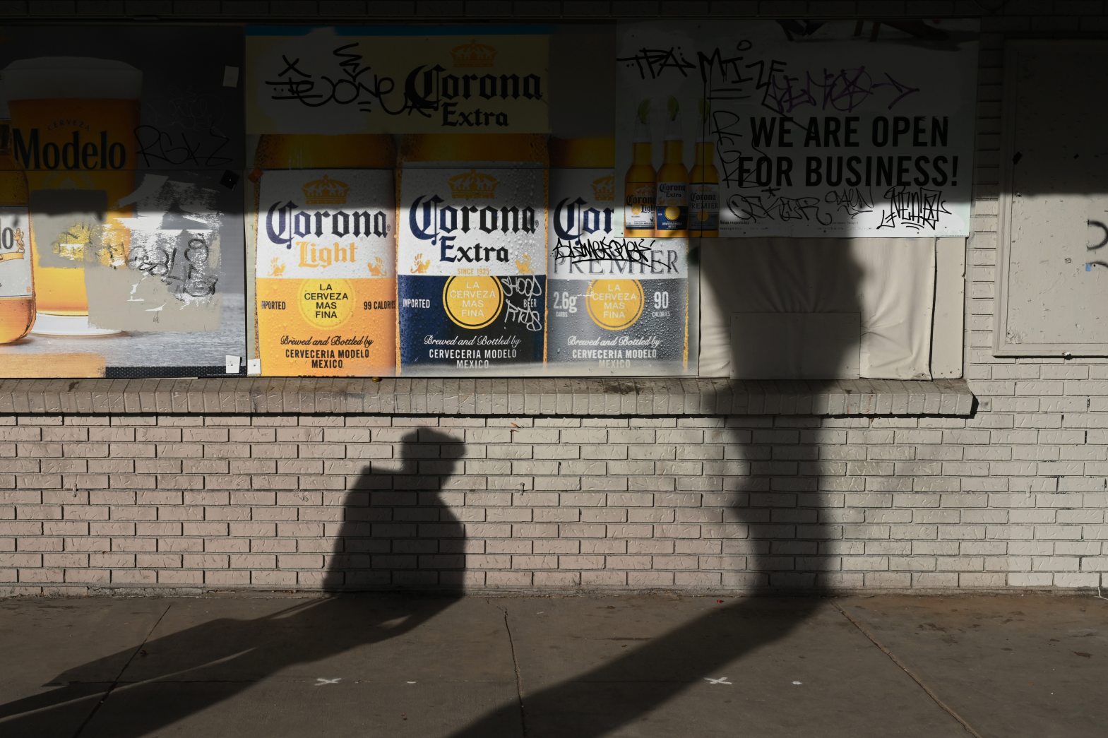 A pedestrian walks past advertisements for beer at a liquor store along East Colfax Avenue in Denver.