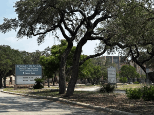A sign that reads Ronald Reagan High Schools sits in front of a building.