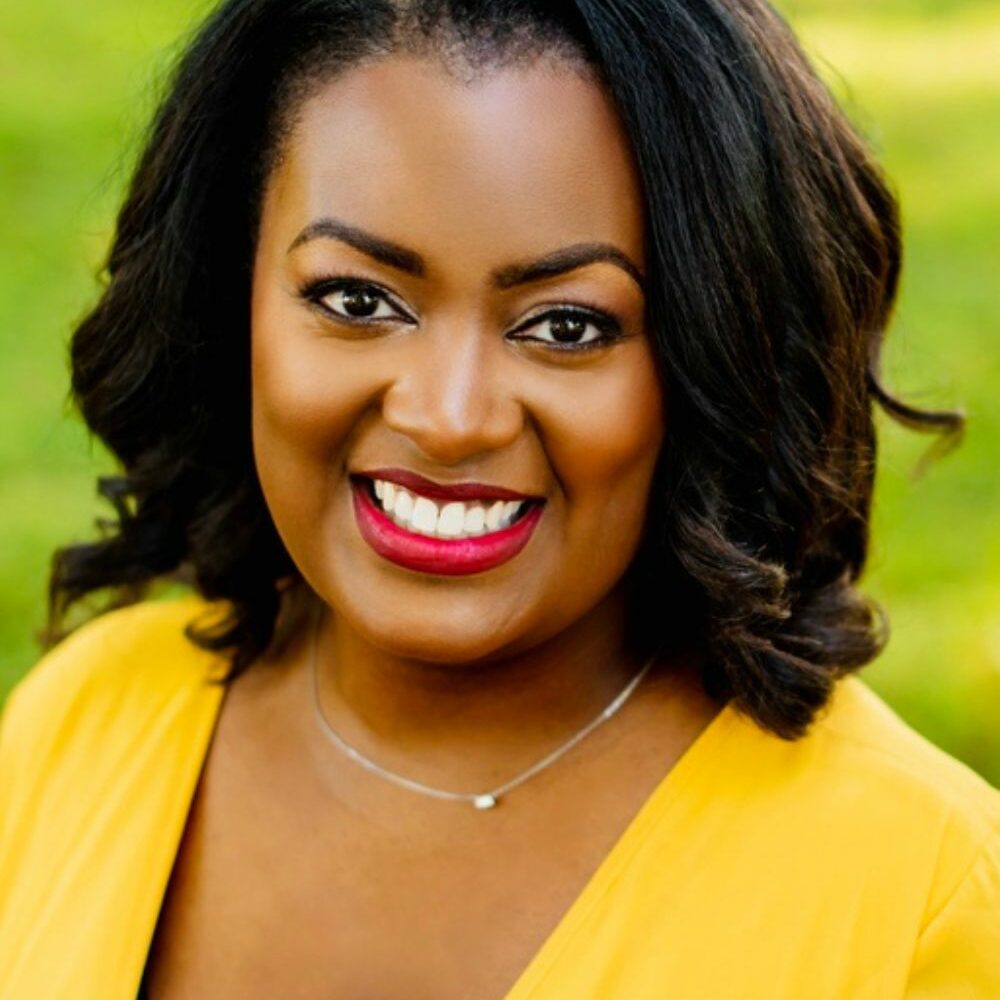 Photo of Amanda smiling with long black hair in a yellow sweater.