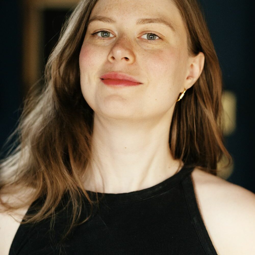 Image of Emi in a black dress looking at the camera.