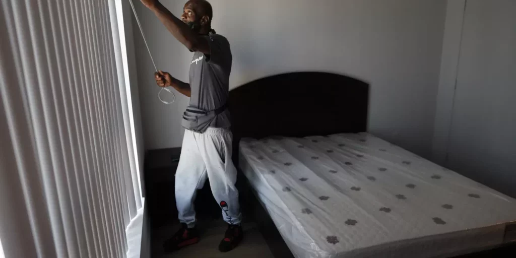 Donald Winston adjusts the blinds moments after moving into his new apartment — the first-ever home of his own. ©Robert Gauthier/Los Angeles Times