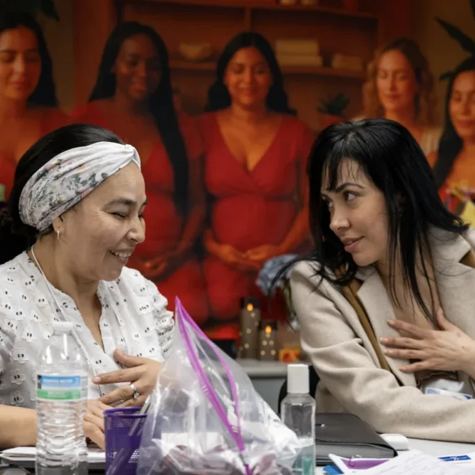Juana Lenny (left) and Diana Luna (right) discuss an assignment as part of a certification program for Spanish-speaking women to become doulas. They are training at the Hispanic Health Council in Hartford on March 31, 2026. (Tyler Russell / Connecticut Public)