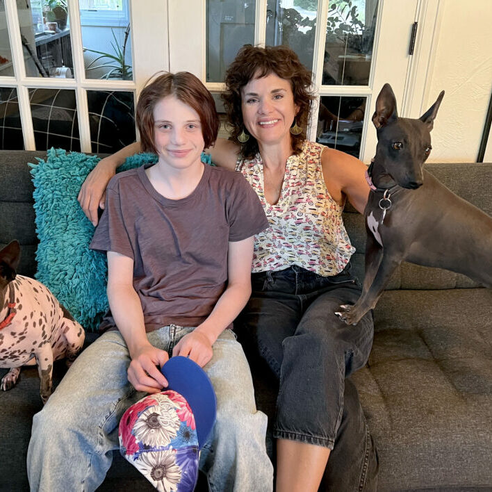 Maddie Maes and her mother sit on their couch.